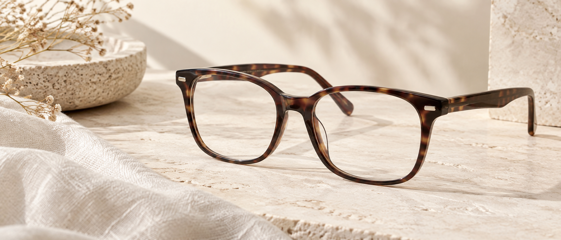 Tortoiseshell optical glasses with clear lenses on a warm cream surface